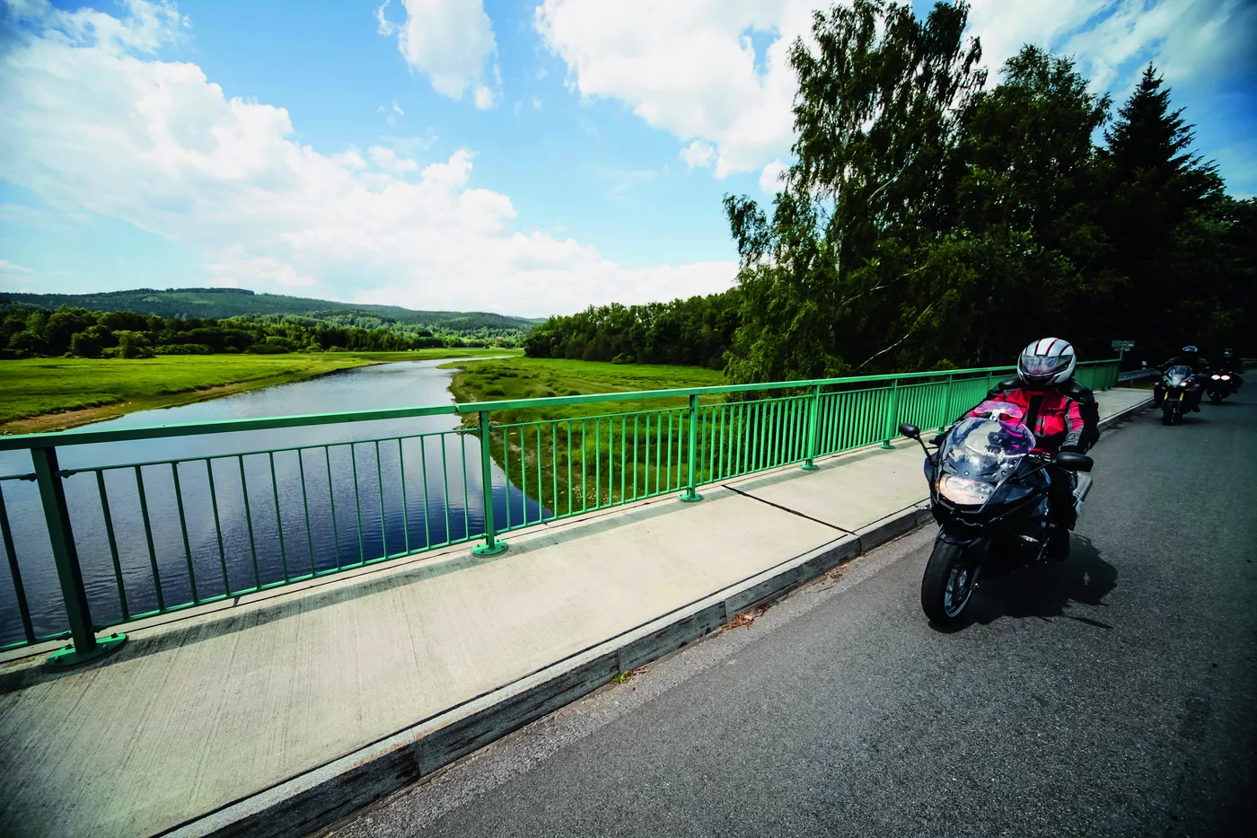 Motorräder auf einer grünen Stahlbrücke über einen Fluss Motorräder auf einer grünen Stahlbrücke über einen Fluss
